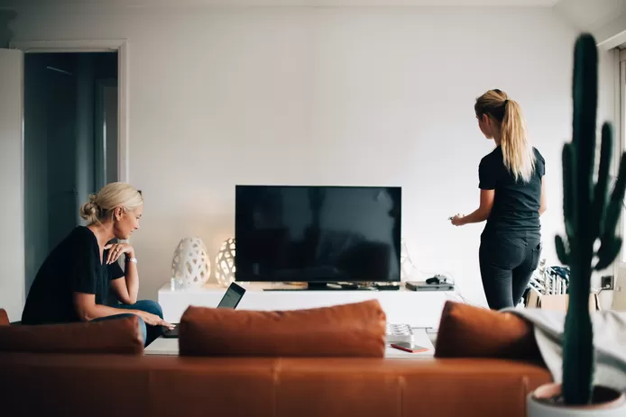 Twee vrouwen in de living kijken hoe ze tv kunnen kijken via een app