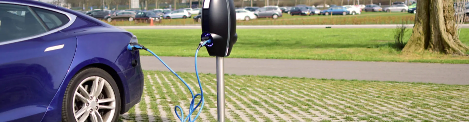 Elektische wagen laadt op aan laadpaal op parkeerplaats.