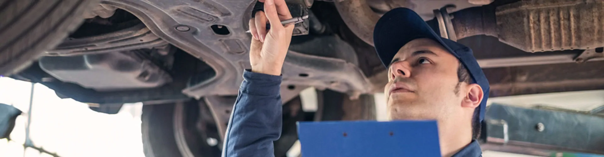 Garagist controleert tijdens autokeuring de onderkant van de auto.