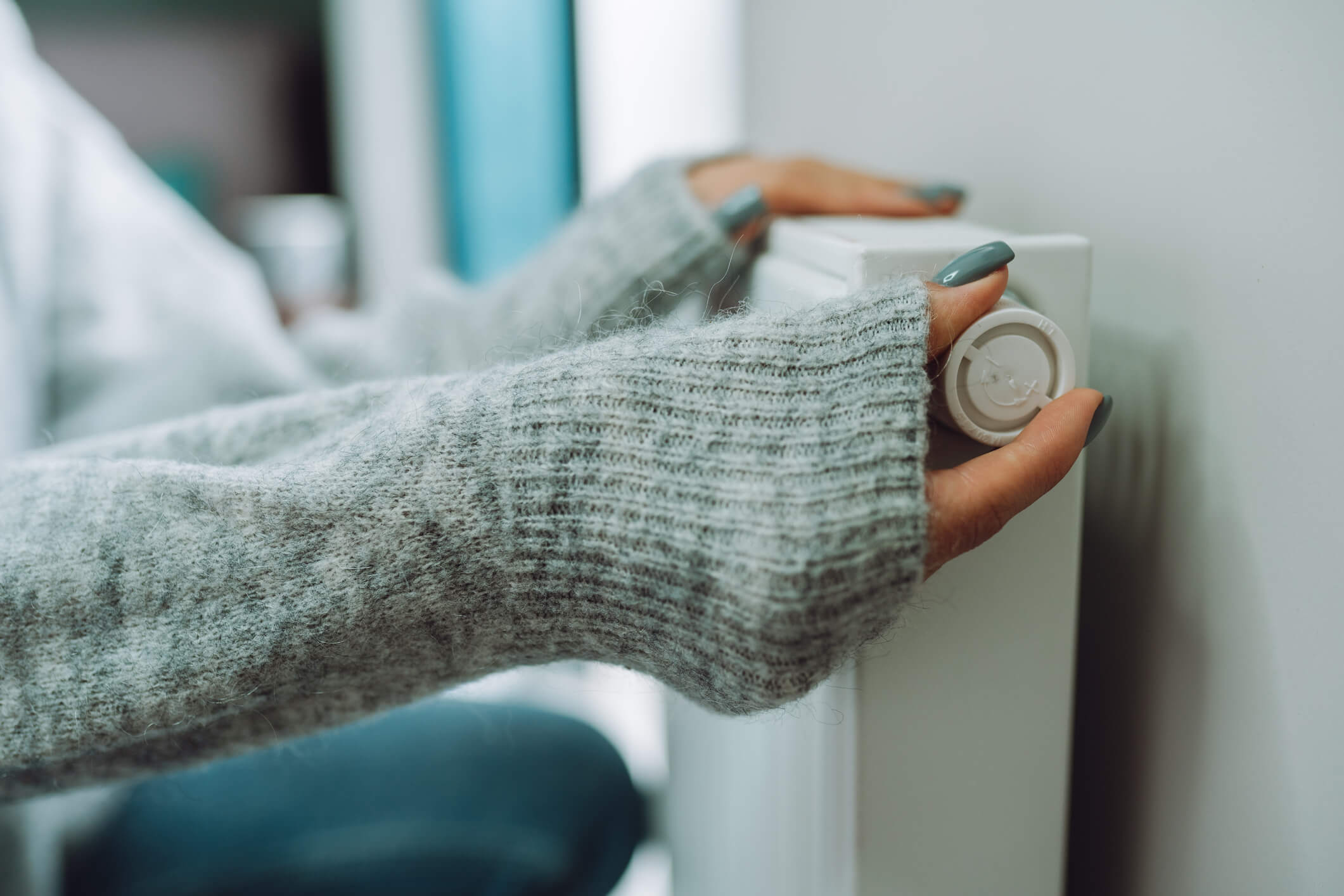 Vrouw met warme trui zet verwarming aan