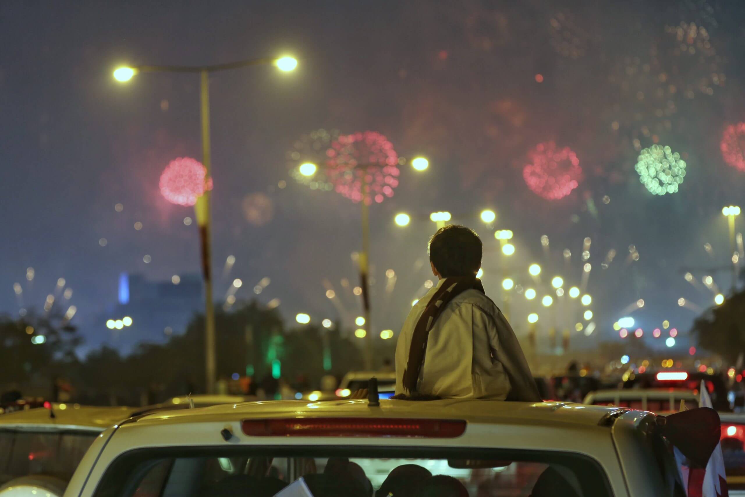 Jongetje kijkt naar vuurwerk vanop auto