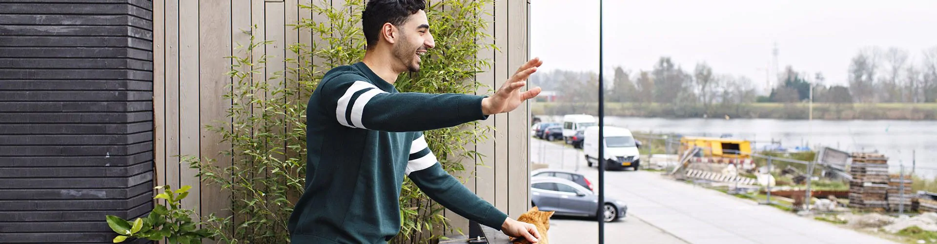 Man wuift vanop het balkon naar een persoon beneden.