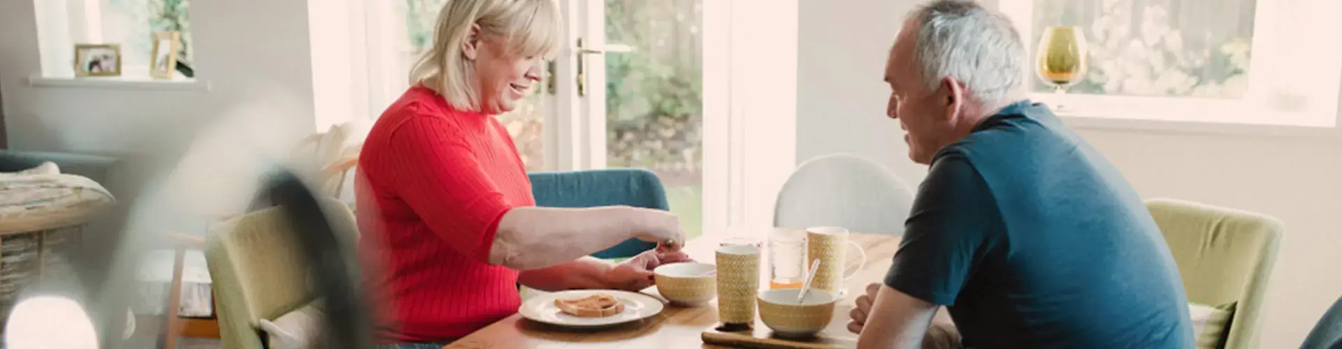 Oudere man en vrouw zitten aan ontbijttafel in vakantiehuis