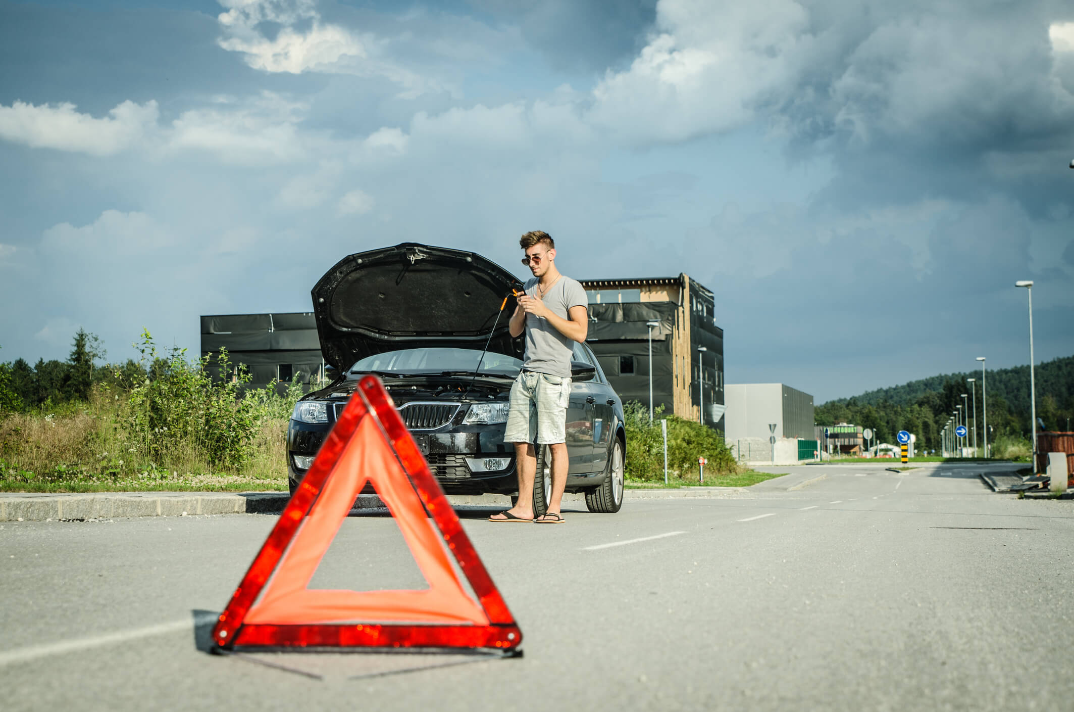 Man staat met auto aan de zijjkant van de weg en belt pechverhelping.