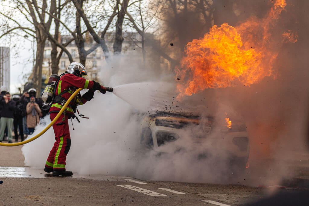 A firefighter seen trying to extinguish a burning car after