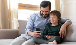 Vader en zoon kijken naar de smartphone.