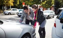 Twee mensen vullen het aanrijdingsfomulier in nadat ze met hun auto tegen elkaar gebotst zijn op een privé parking.