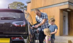 Vader en kinderen laden de auto op met een laadpaal.