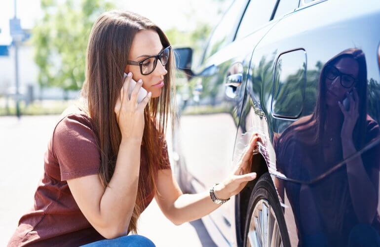 Vrouw ontdekt schade aan haar geparkeerde wagen en belt verzekeraar.