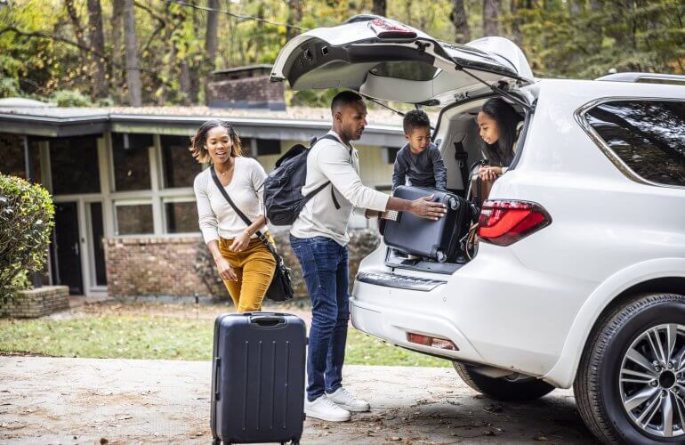 Gezin gaat met de auto op reis en laadt hun koffers in de auto in.