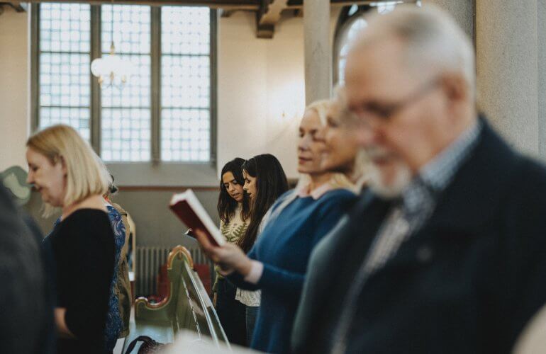 Familieleden van overledene zingen Afscheid van een vriend tijdens begrafenis in de kerk