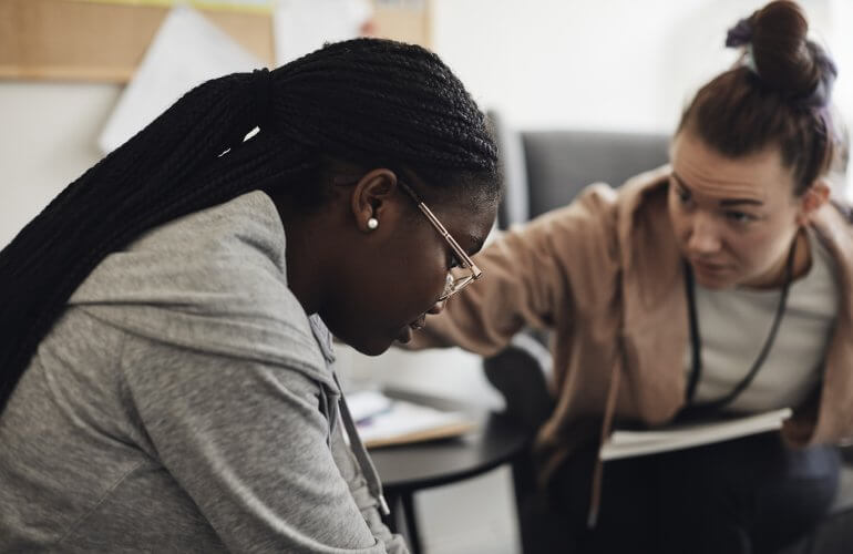 Psycholoog geeft verzekerde van DELA een schouderklopje bij sessie.