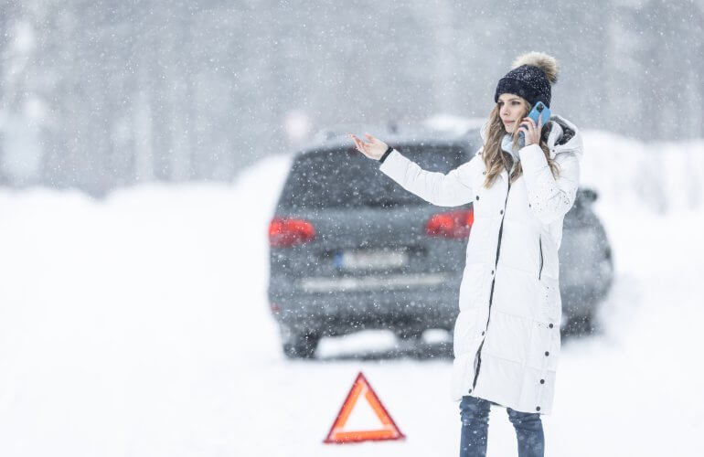 Vrouw heeft autopech op besneeuwde weg en belt pechverhelping