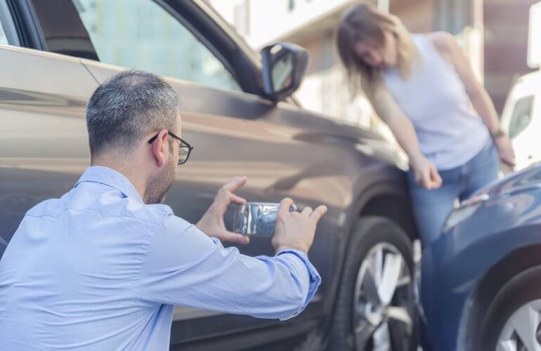 Man neemt foto van auto die tegen elkaar gebotst zijn