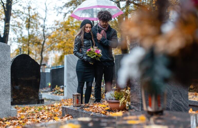 Koppel rouwt bij graf van overleden familielid.