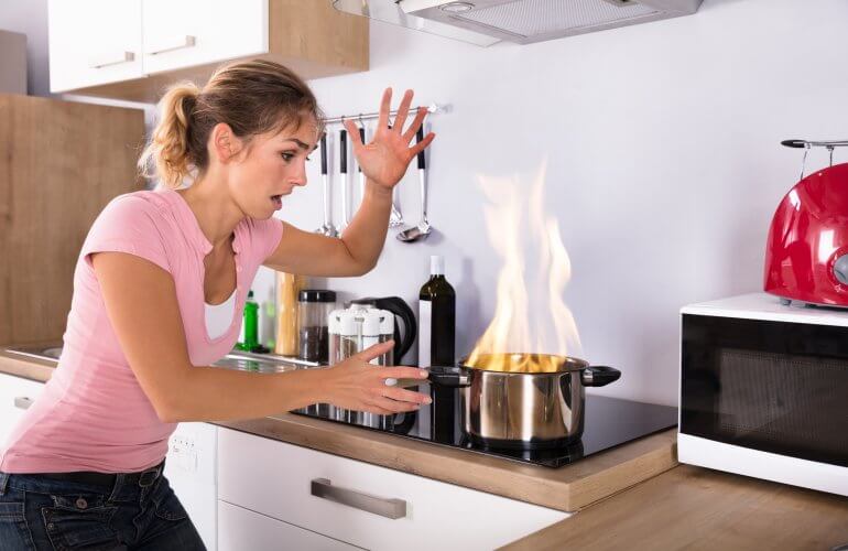 Vrouw ziet brandende kookpot op het vuur staan.